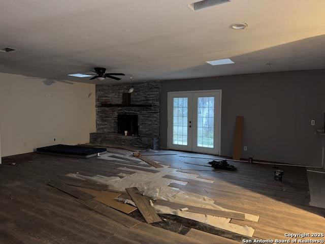 unfurnished living room with hardwood / wood-style flooring, ceiling fan, a fireplace, and french doors