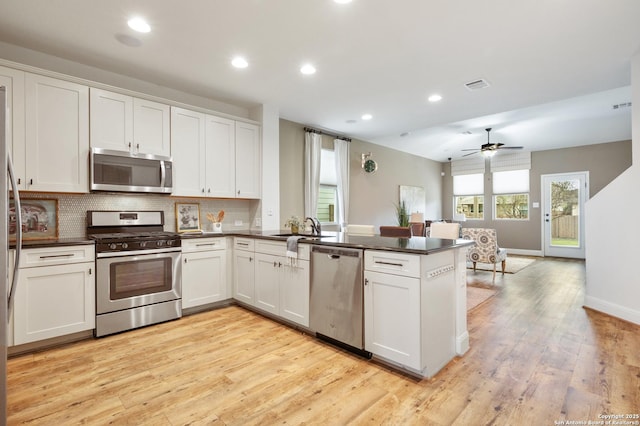 kitchen with kitchen peninsula, light wood-type flooring, stainless steel appliances, ceiling fan, and white cabinets