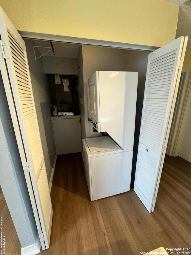 laundry room featuring stacked washer and dryer and hardwood / wood-style floors