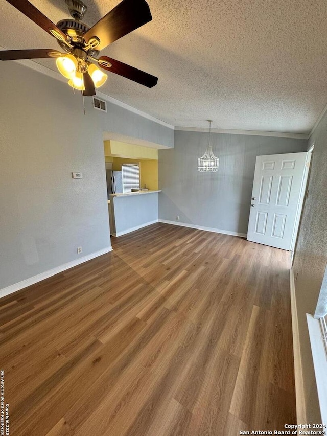 unfurnished living room featuring wood-type flooring, a textured ceiling, ceiling fan, and ornamental molding