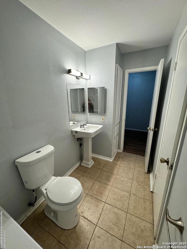 bathroom featuring tile patterned floors, a textured ceiling, and toilet