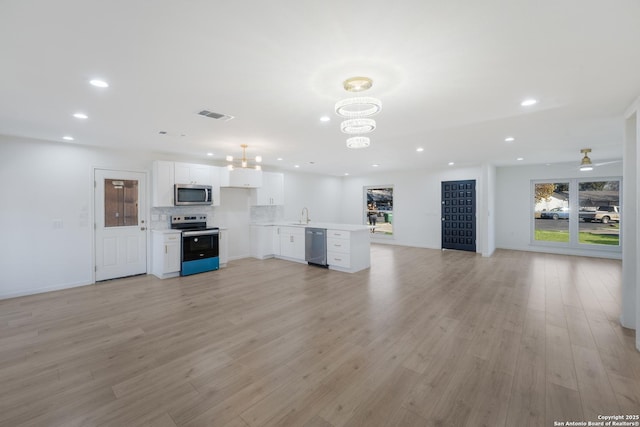 unfurnished living room featuring sink, ceiling fan with notable chandelier, and light hardwood / wood-style flooring