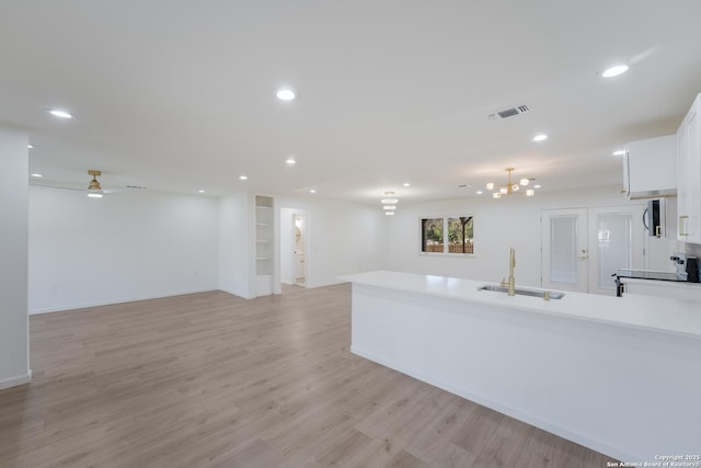 kitchen featuring electric stove, sink, light hardwood / wood-style flooring, white cabinets, and ceiling fan with notable chandelier