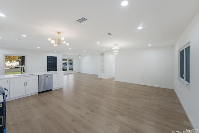 kitchen featuring sink, light wood-type flooring, dishwasher, ceiling fan with notable chandelier, and white cabinets