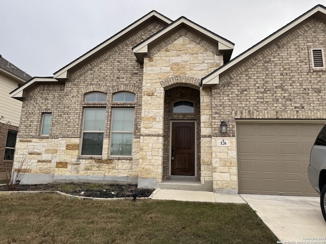 exterior space with a garage, stone siding, and brick siding