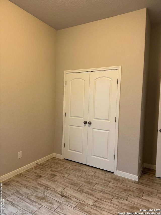 unfurnished bedroom featuring baseboards, a closet, and wood tiled floor