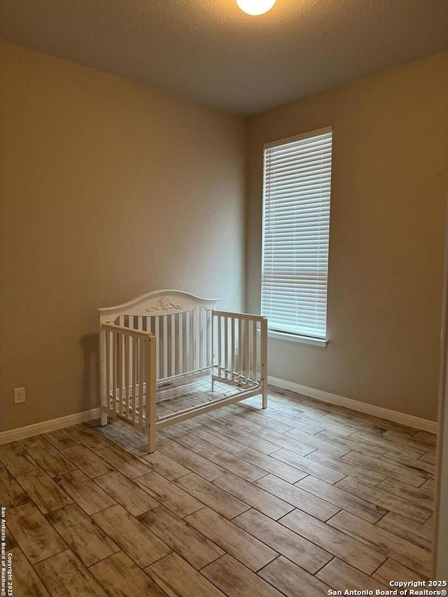 spare room with wood tiled floor, a textured ceiling, and baseboards