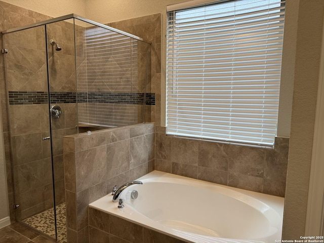 bathroom featuring a stall shower, a bath, and a textured wall