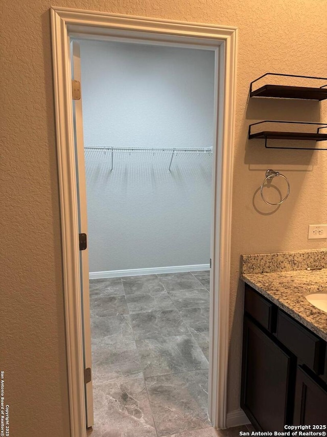 interior space featuring a walk in closet, vanity, and baseboards