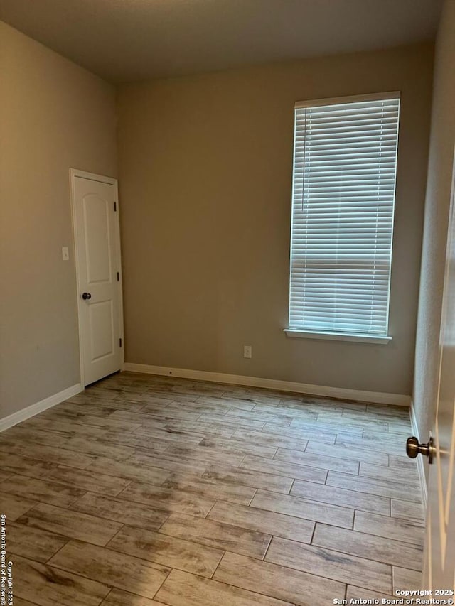 unfurnished room with baseboards and wood finished floors