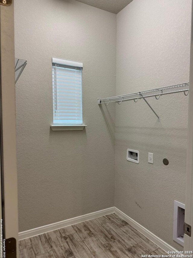 clothes washing area featuring washer hookup, hookup for an electric dryer, wood finished floors, laundry area, and baseboards