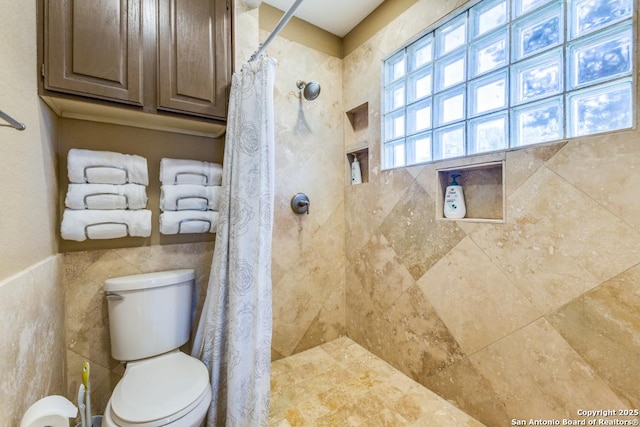 bathroom featuring a shower with curtain, toilet, and tile walls