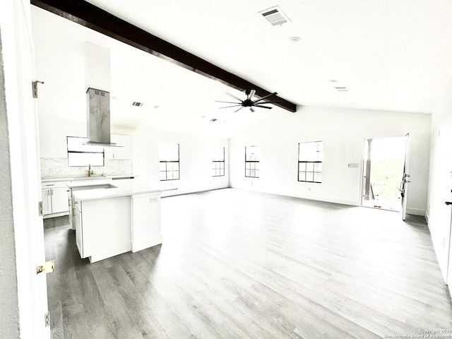 unfurnished living room with wood-type flooring, vaulted ceiling with beams, ceiling fan, and sink