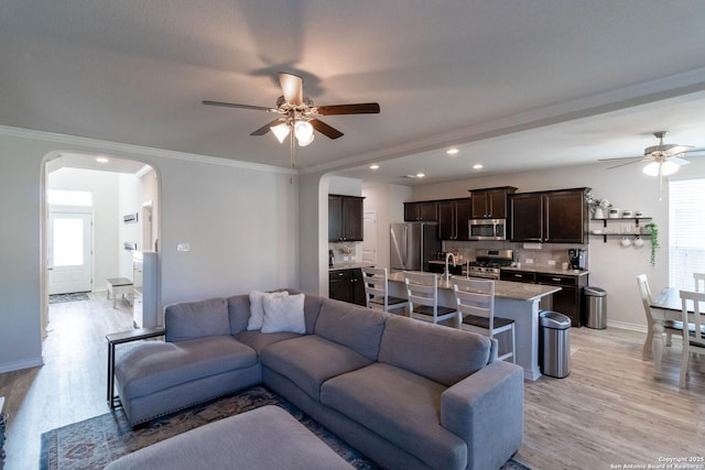 living room with crown molding, light hardwood / wood-style flooring, and ceiling fan