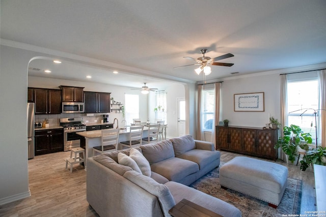 living room featuring crown molding, ceiling fan, and light wood-type flooring