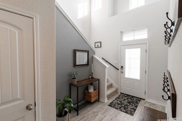 entryway featuring a wealth of natural light, light hardwood / wood-style flooring, and a high ceiling