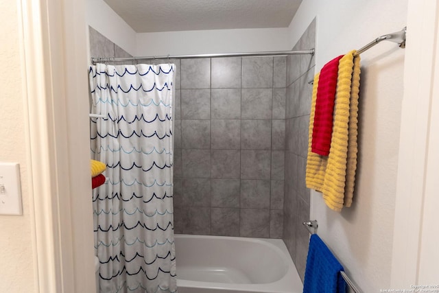 bathroom with shower / bathtub combination with curtain and a textured ceiling