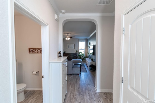 hall with ornamental molding and light hardwood / wood-style floors