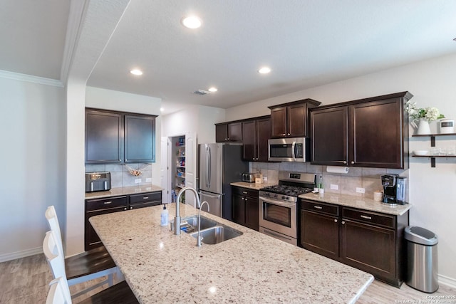 kitchen with sink, tasteful backsplash, a center island with sink, a kitchen breakfast bar, and stainless steel appliances