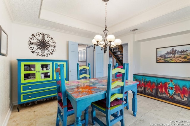 dining room featuring tile patterned floors, ornamental molding, a textured ceiling, a raised ceiling, and a chandelier