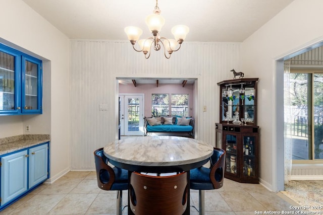 tiled dining space with beam ceiling, wooden walls, and a chandelier