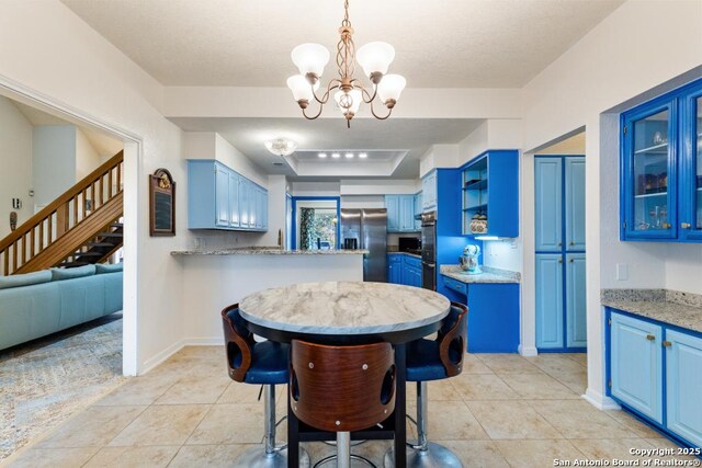 kitchen with blue cabinetry, stainless steel refrigerator with ice dispenser, a chandelier, and light stone counters