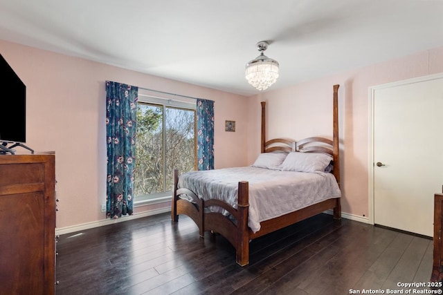 bedroom with dark hardwood / wood-style floors and a chandelier