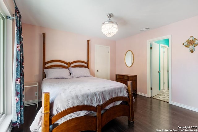 bedroom with a notable chandelier and dark wood-type flooring