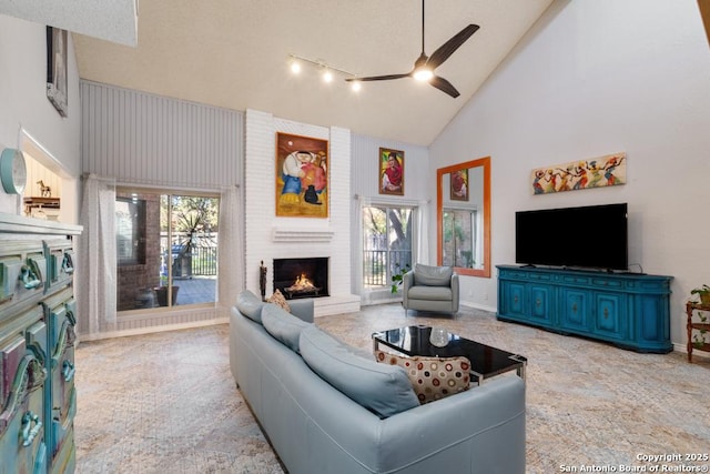 living room featuring a fireplace, high vaulted ceiling, and ceiling fan