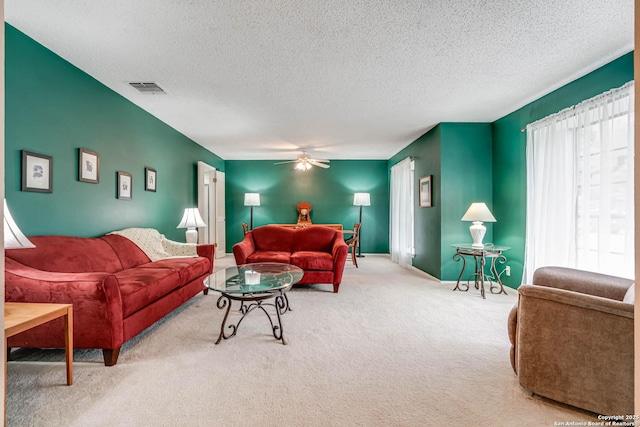 carpeted living room with ceiling fan and a textured ceiling