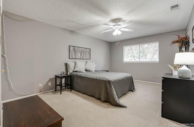 bedroom featuring ceiling fan, light carpet, and a textured ceiling