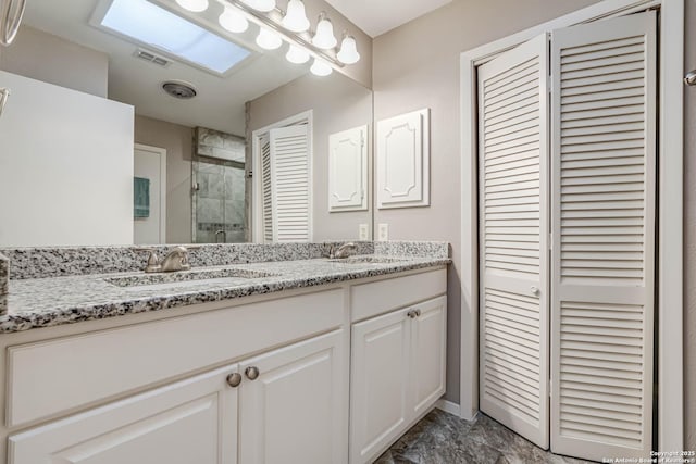 bathroom with a skylight, a shower with door, and vanity