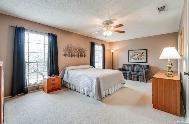 bedroom with ceiling fan, multiple windows, carpet, and a textured ceiling