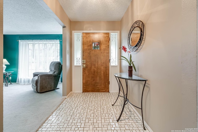 carpeted foyer featuring a textured ceiling