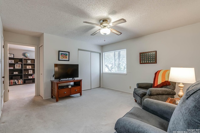 carpeted living room featuring ceiling fan and a textured ceiling