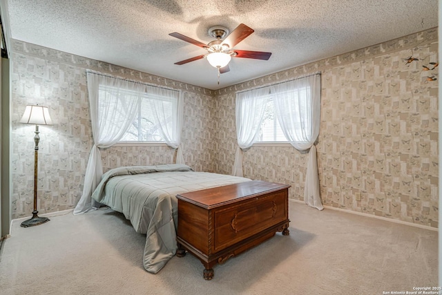 bedroom with ceiling fan, light colored carpet, and a textured ceiling