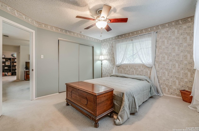 carpeted bedroom with a textured ceiling, ceiling fan, and a closet