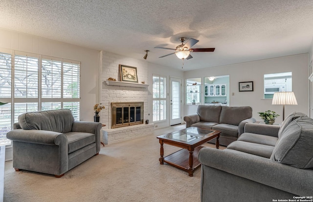 carpeted living room featuring ceiling fan, a brick fireplace, and a textured ceiling