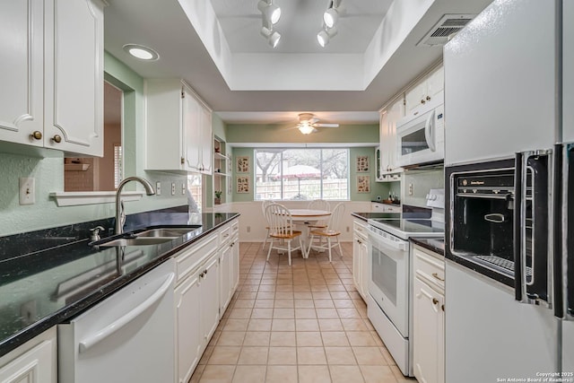 kitchen with white appliances, white cabinetry, sink, a raised ceiling, and light tile patterned floors