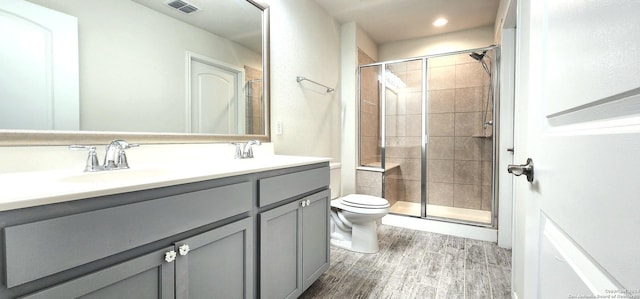 bathroom with toilet, a shower with door, vanity, and hardwood / wood-style flooring