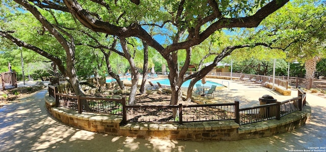 view of home's community with a pool and a patio