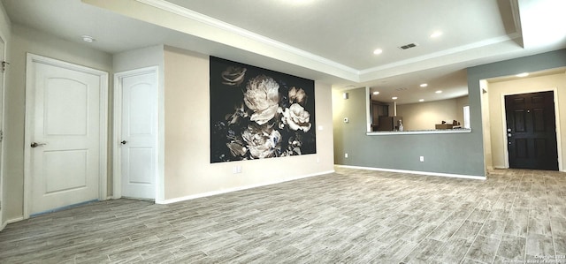 interior space featuring light hardwood / wood-style floors, crown molding, and a tray ceiling