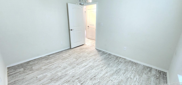 unfurnished room with a chandelier and light hardwood / wood-style flooring