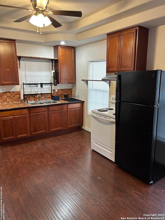 kitchen featuring backsplash, black refrigerator, white range, sink, and island range hood