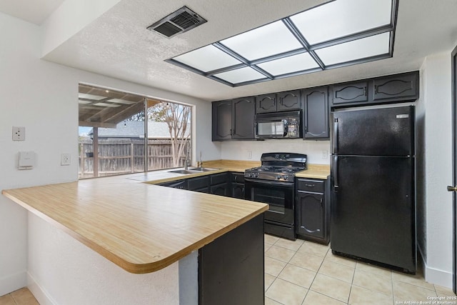 kitchen featuring sink, kitchen peninsula, light tile patterned floors, and black appliances