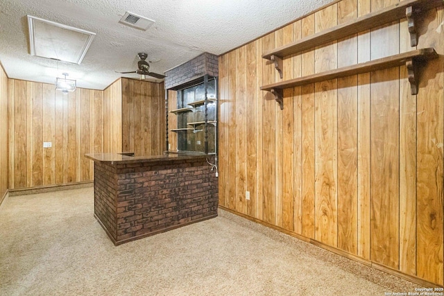 bar with ceiling fan, wooden walls, light carpet, and a textured ceiling