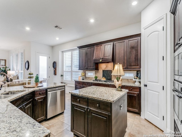 kitchen featuring a kitchen island, dark brown cabinetry, sink, and appliances with stainless steel finishes