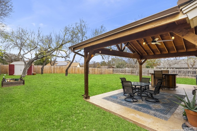 view of yard with ceiling fan, a storage unit, and a patio