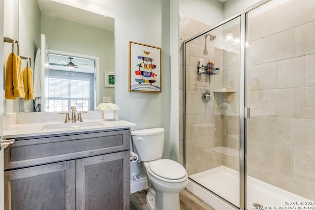 bathroom with vanity, toilet, ceiling fan, and a shower with shower door