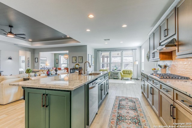 kitchen featuring a wealth of natural light, stainless steel appliances, sink, a center island with sink, and green cabinets